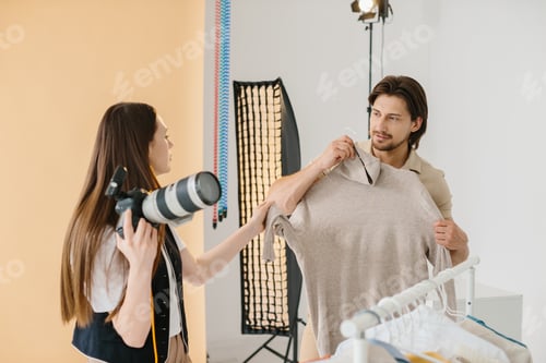 Preview: Photographer and Male Model Selecting Outfit for Photoshoot in Studio