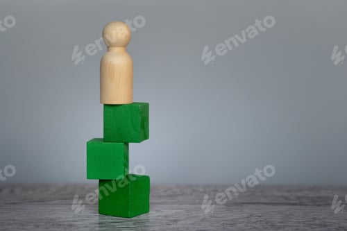 Preview: Doll standing on top of unstable wooden block on table with copy space