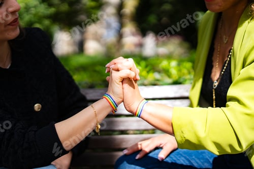 Preview: Two women holding hands showing rainbow bracelets in support of lgbtq community