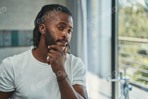 Preview: Man touching his beard with one hand before mirror