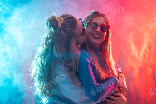 Preview: Two young blonde caucasian women dancing in disco, kissing dancing at party, red and blue led smoke