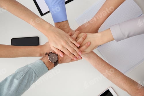 Preview: Young people holding hands together over table, top view. Team victory concept