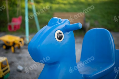 Preview: Closeup shot of a blue toy horse in a playground on a blurred background