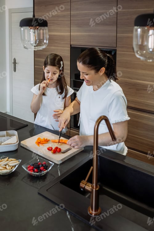 Preview: Mother preparing snack for school while her daughter eats carrot