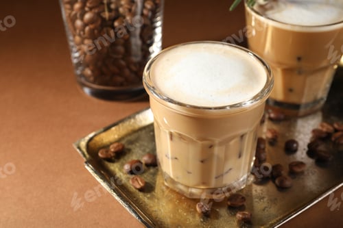 Preview: Refreshing iced coffee with milk in glasses on brown table, closeup