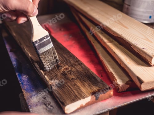 Preview: close up paintbrush painting the wooden bar in workshop on table