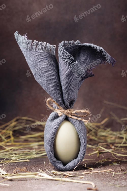 Preview: Easter egg decorated like a bunny on a brown concrete background