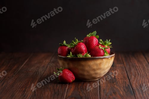 Preview: Fresh red strawberries in a rustic bowl on a dark wooden background. Front view
