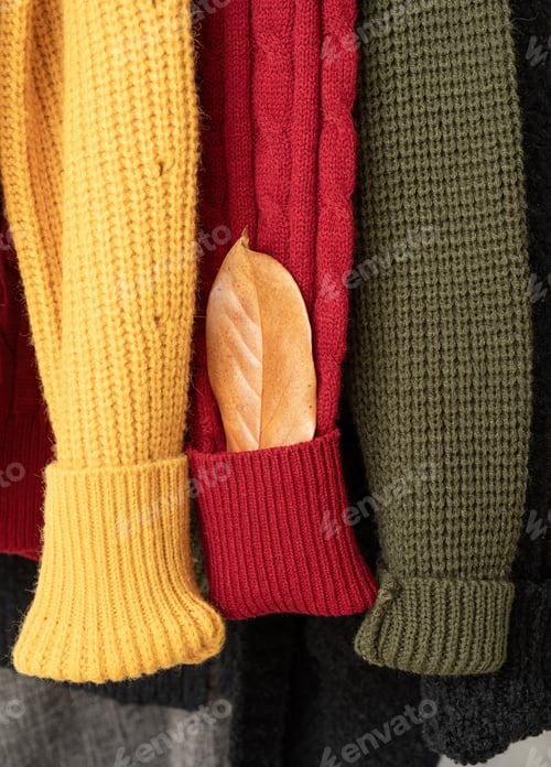 Preview: Row of different colorful Knitted sweaters hang on hangers, white background