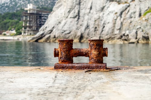 Preview: Knechts on pier against backdrop of sea and mountains and Abandoned hotel.