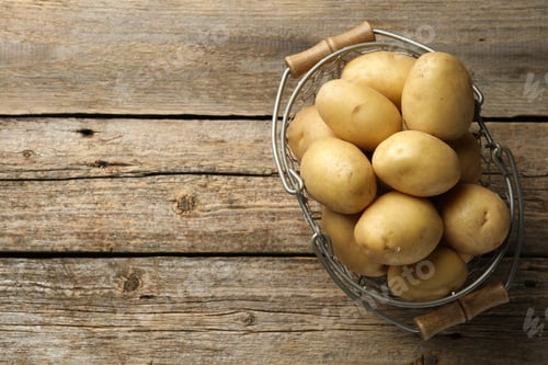 Preview: Fresh potatoes in basket on wooden table, top view. Space for text