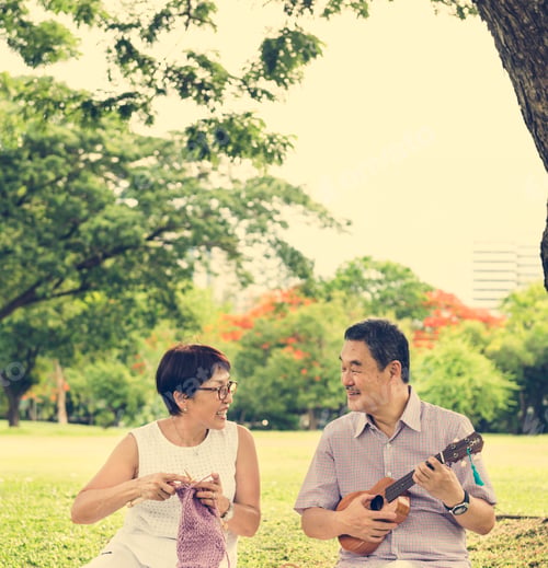 Senior Couple Knitting and Playing Music in Park