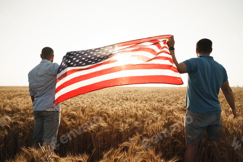 Preview: Two men patriots holding US flag above wheat field