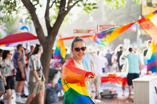 Preview: Woman in rainbow flag walking at Pride supporting LGBT rights. Activism. Support queer. Minorities.