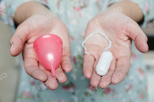 Preview: Woman holding tampon and menstrual cup in her hands