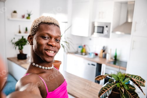 Preview: Happy black transsexual man taking selfie in modern apartment at kitchen