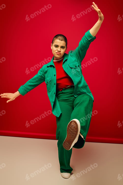 Preview: fashion forward, vibrant backdrop, young woman in stylish attire gesturing while posing on red