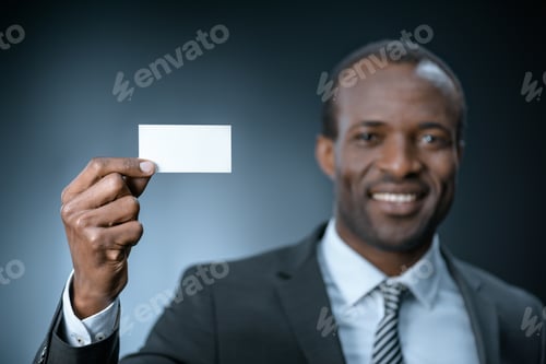 Preview: selective focus of smiling african american businessman showing business card isolated on black