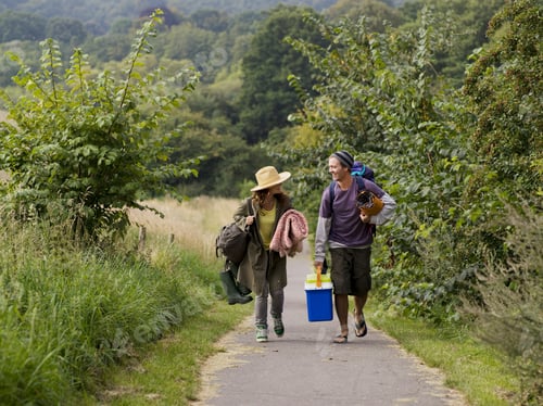 Preview: Couple enjoying a leisurely walk down a country path with a picnic basket