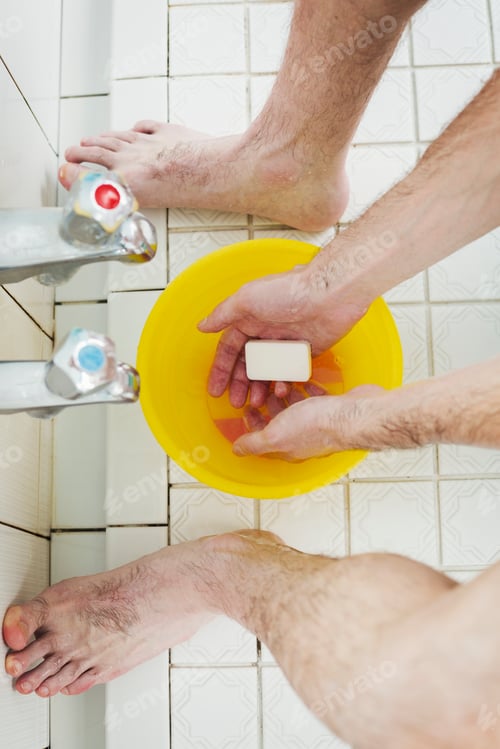 Preview: A man standing in a shower with soap in his hands, washing.