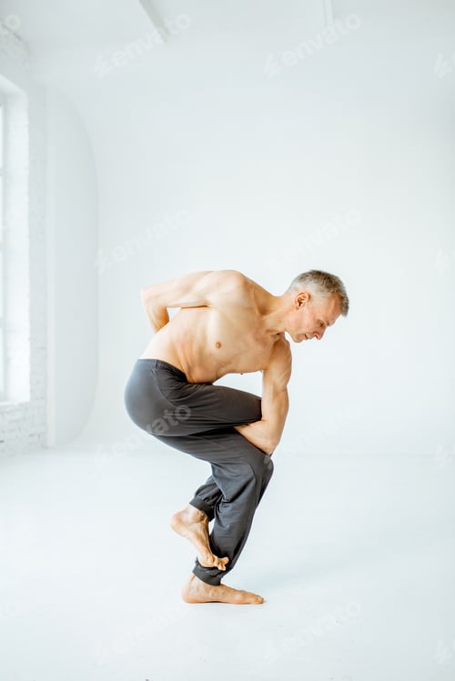 Preview: Senior man practising yoga indoors