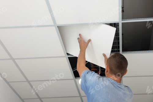 Vista previa: Instalación en techo suspendido. Constructor que trabaja con baldosas de PVC, vista de ángulo bajo