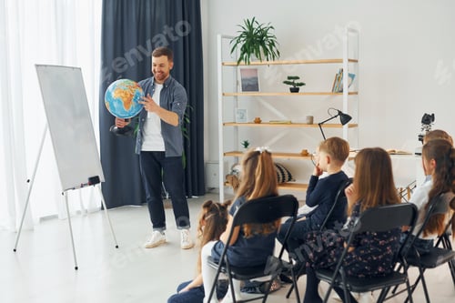 Preview: Teaching geography lesson by using Earth globe. Group of children students in class