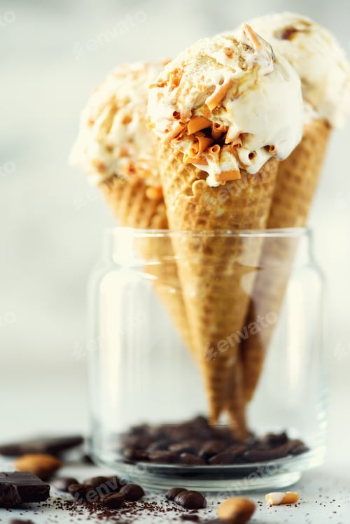 Aperçu: Caramel sauce ice cream in waffle cone with coffee beans on grey stone background. Summer food