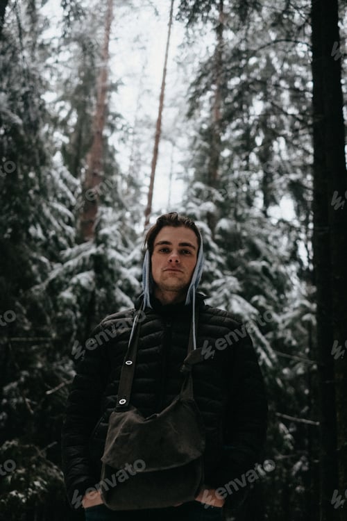 Preview: handsom young man in warm clothes in winter forest