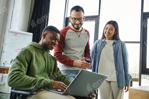Preview: smiling african american businessman working on laptop near asian woman and bearded colleague with