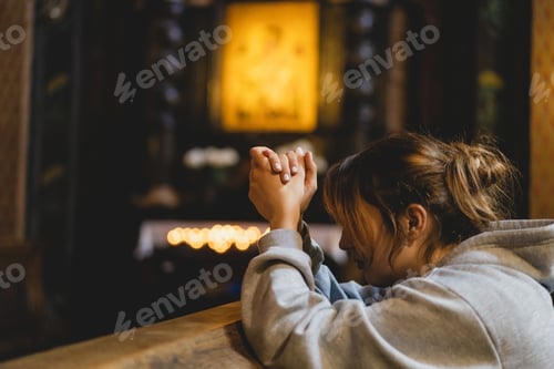 Preview: Woman praying on her knees in an ancient Catholic temple to God.