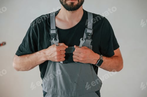 Preview: Standing in grey colored uniform. The man is making repairs in the apartment