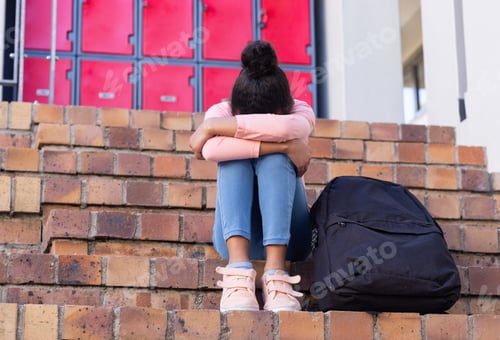 Preview: Sitting on school steps, african american girl with backpack feeling sad and alone