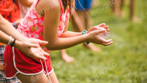 Preview: Group of happy, cheerful children playing in waterballoon game in the park and having fun together