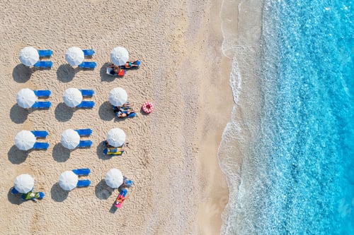 Preview: Aerial view of blue sea, sandy beach with umbrellas at sunset