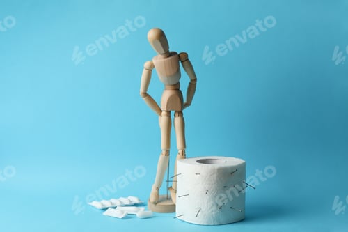 Preview: Wooden man, candles and toilet paper on blue background. Hemorrhoids