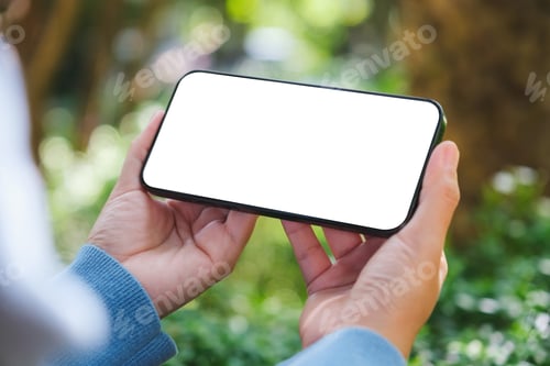 Preview: Mockup image of a woman holding mobile phone with blank white desktop screen in the outdoors