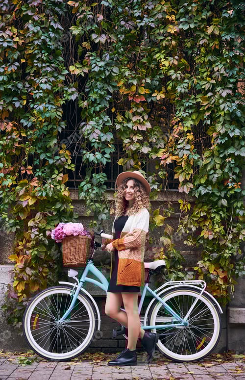 Preview: Cheerful young woman with bicycle standing on the street.