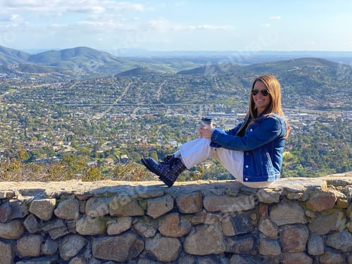 Preview: A woman sits on a stone wall,Gorgeous view of San Diego County as seen from the top of Mt. Helix