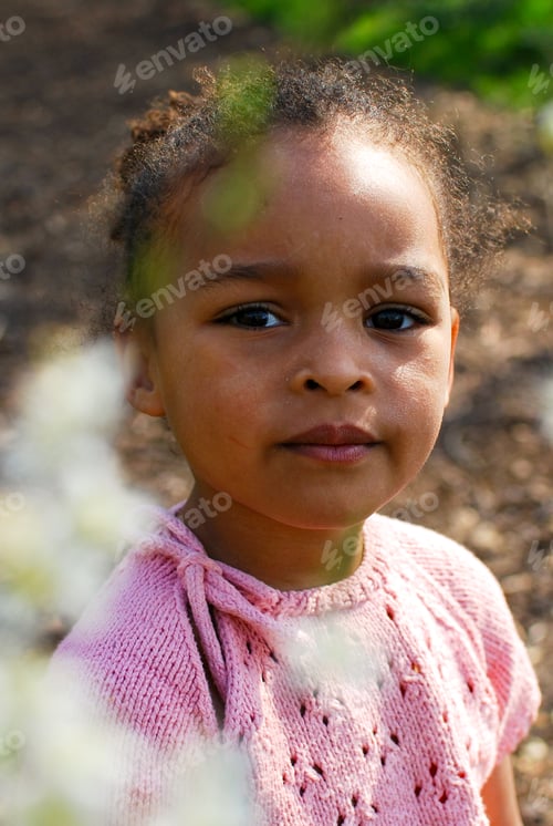 Preview: Portrait of a little girl of mixed race in nature wearing a knit top. Beauty, diversity