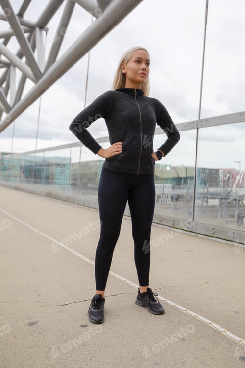Preview: Pretty Woman in Black Workout Wear Standing At Modern Bridge In City
