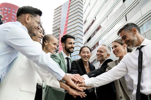 Vista previa: Group of smiling multiethnic businessman and businesswoman holding hands together outside
