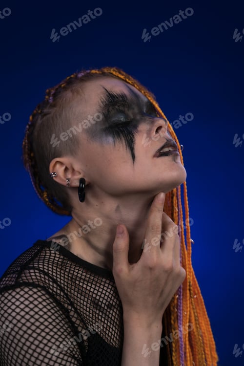 Preview: Headshot of woman with eyes closed, orange color braids hairdo, spooky stage make up painted on face