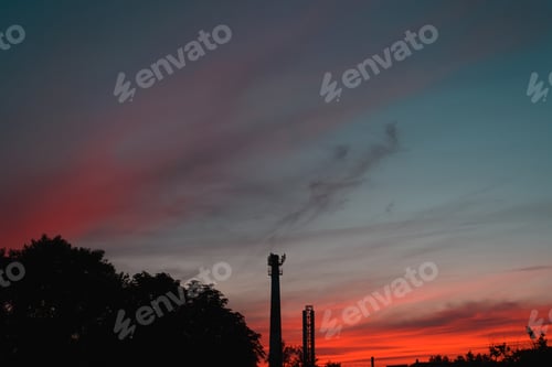 Preview: Silhouette of pipes of chemical industrial factory against backdrop of dramatic landscape of red