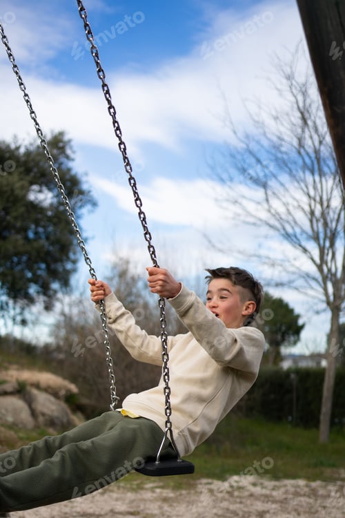 Preview: Child having fun swinging high on a swing in a playground during a sunny day