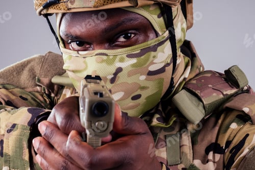 Preview: american man in camouflage suit aiming with a pistol studio shot