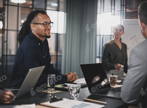 Preview: Smiling young businessman meeting with coworkers in an office