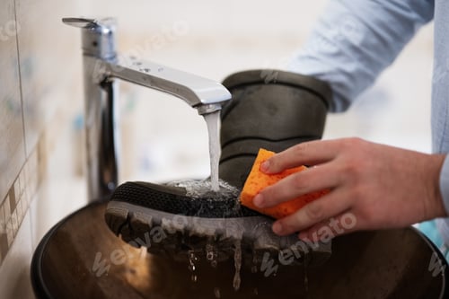 Preview: Сleaning the shoes. Man washes boots in the sink.
