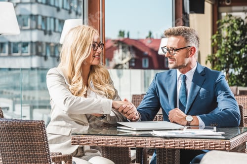 Preview: portrait of business partners shaking hands on business meeting in cafe
