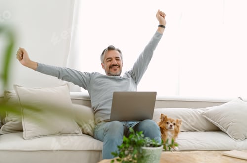 Preview: Middle aged man work from home sit relax on sofa, stretching arms and his lovely dog sit besides